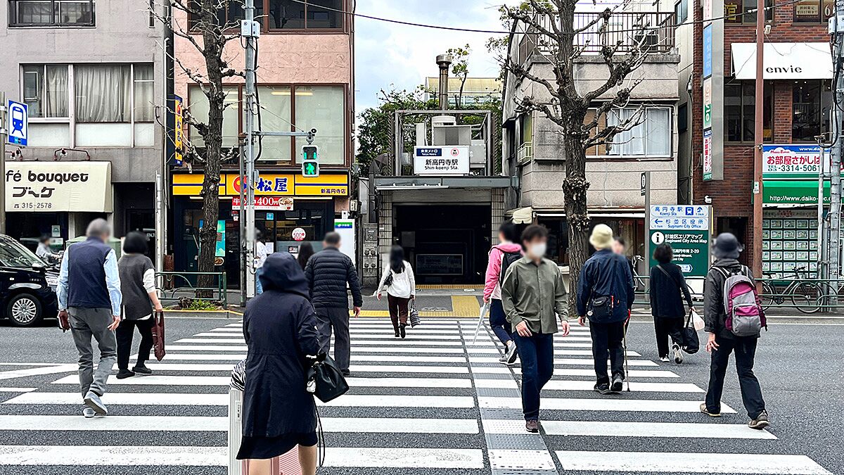 横断歩道を渡る通行人と奥に見える新高円寺駅