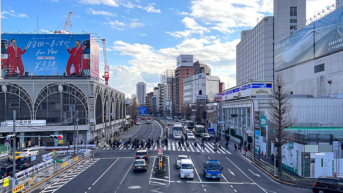 品川駅に面した第一京浜とその横断歩道を渡る歩行者の写真